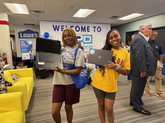 Two graduates hold up new laptops from E2D